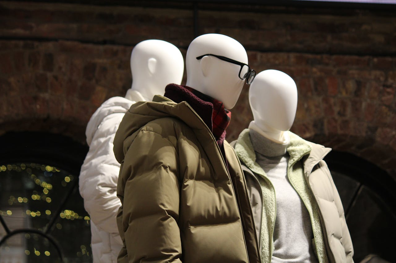 services-06 Mannequins showcasing stylish winter jackets in urban environment under warm lights.